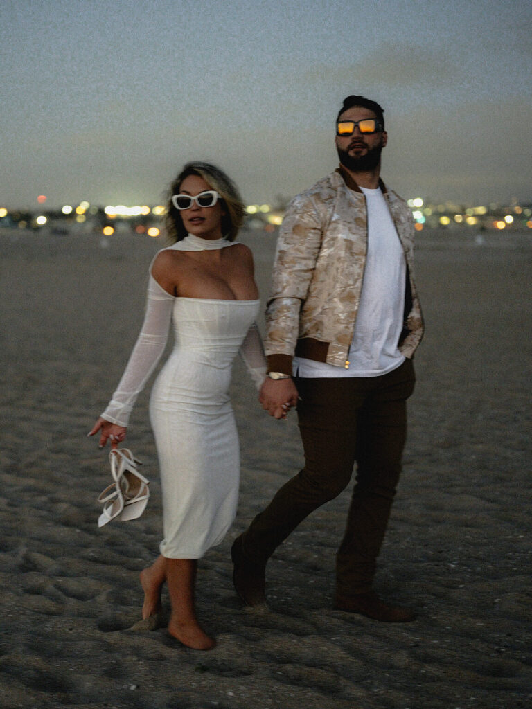 The couple walking the beach hand in hand at blue-hour dusk