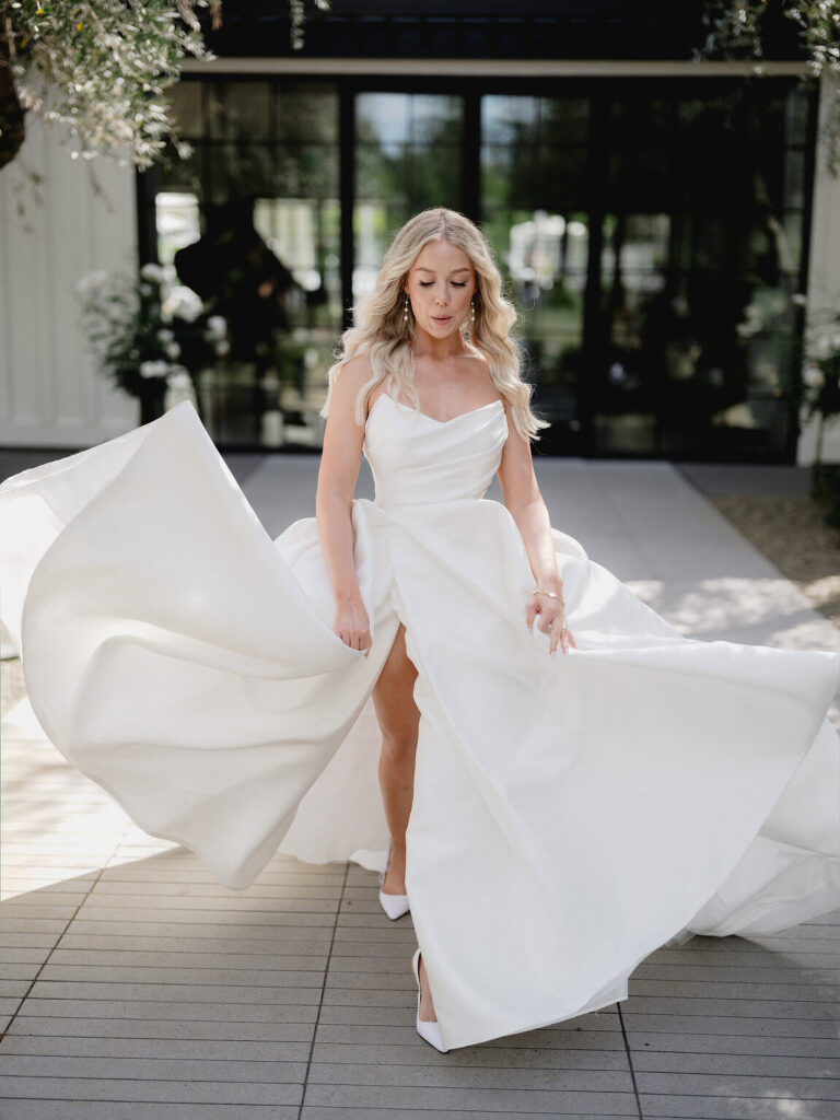 The bride tossing her full skirt in a limestone courtyard