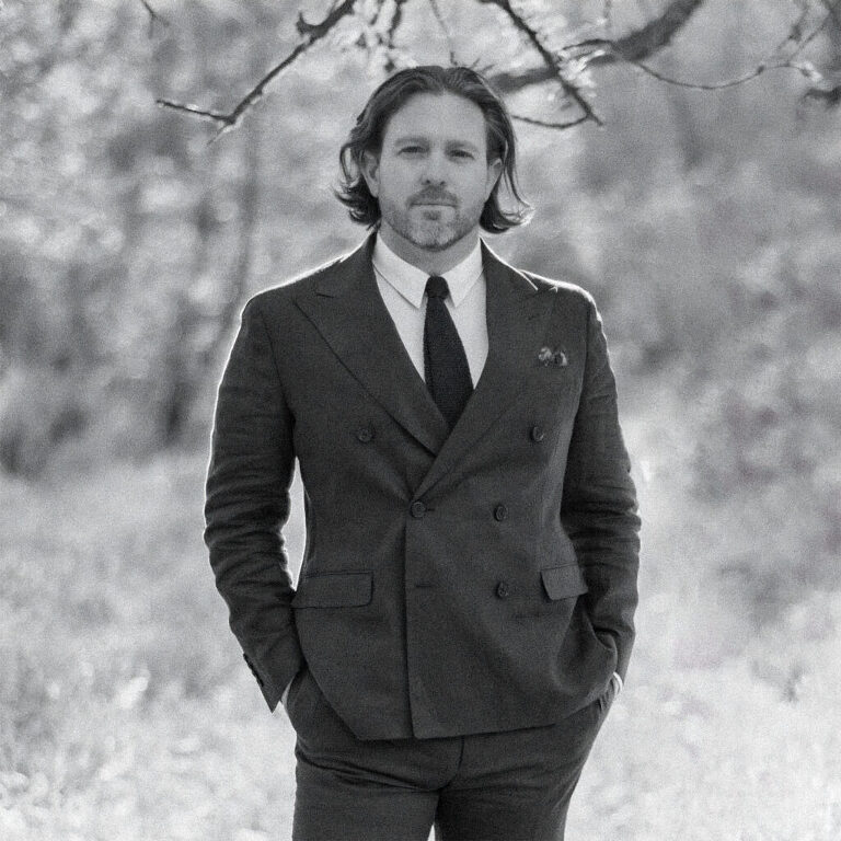 Paul Von Rieter in a double breasted suit and knit tie, photographed in black and white